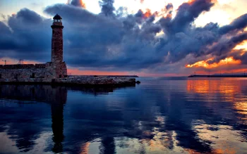 An old lighthouse in the port of Rethymno against the backdrop of a stormy sunset