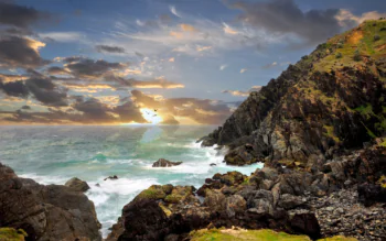 Cliffs and the raging ocean bathed in the rays of the setting sun