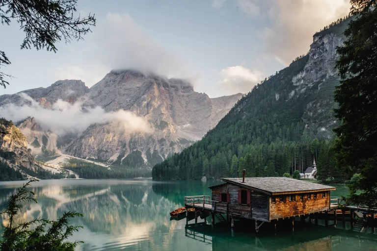 a wooden cabin by lake braies in the italian alps, alps, boats, motorboats, speedboats, churches, clouds, forest, forests, lakes, bodies of water, landscapes, little houses, huts, cottages, mountains, peaks, hills, reflections, trees, nature, world
