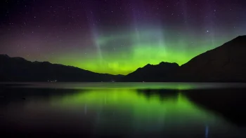 A green glow over the smooth surface of the lake in the mountains