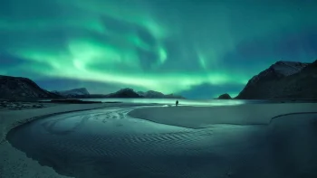 A solitary figure against the backdrop of a glowing sky over a Norwegian fjord