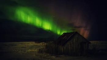 A green glow above an old wooden cabin