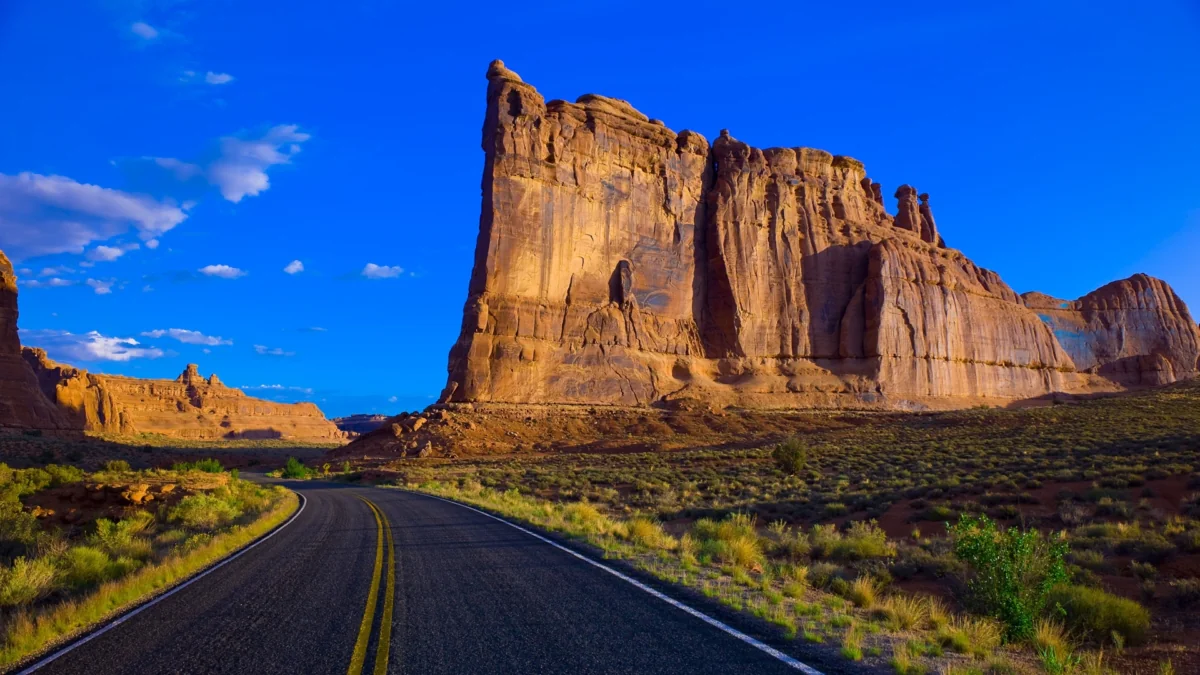 An asphalt road winding through the red rocks of Arches National Park in the United States