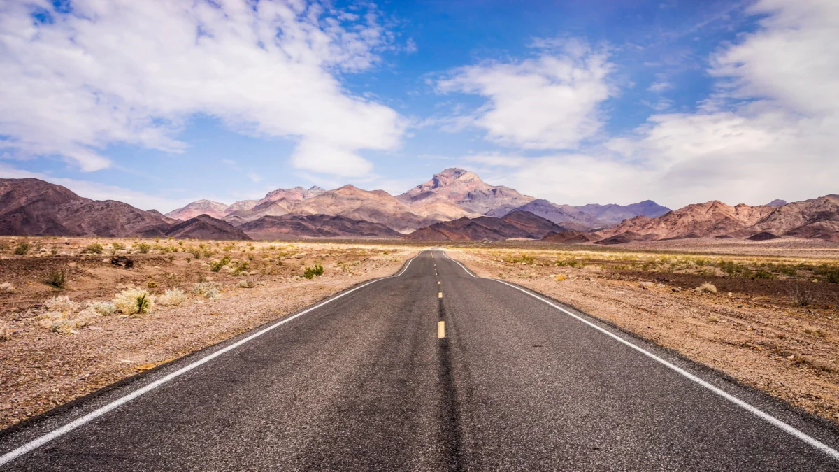 An endless highway in the Nevada desert under a bright midday sky