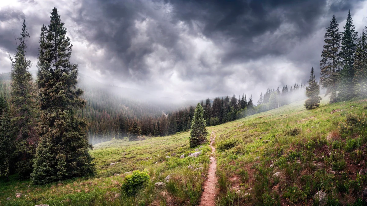 A mountain trail in the Rocky Mountains under stormy skies
