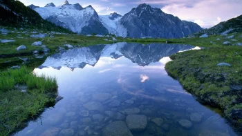 Отражение заснеженных пиков в зеркальной глади горного озера