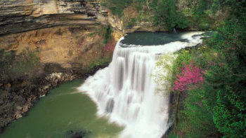Calf Creek Falls, surrounded by rocky cliffs and blossoming trees