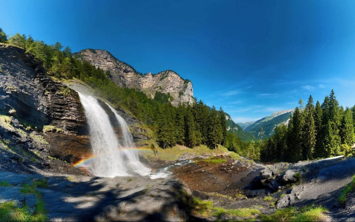 A rainbow at the foot of a waterfall in the Alps