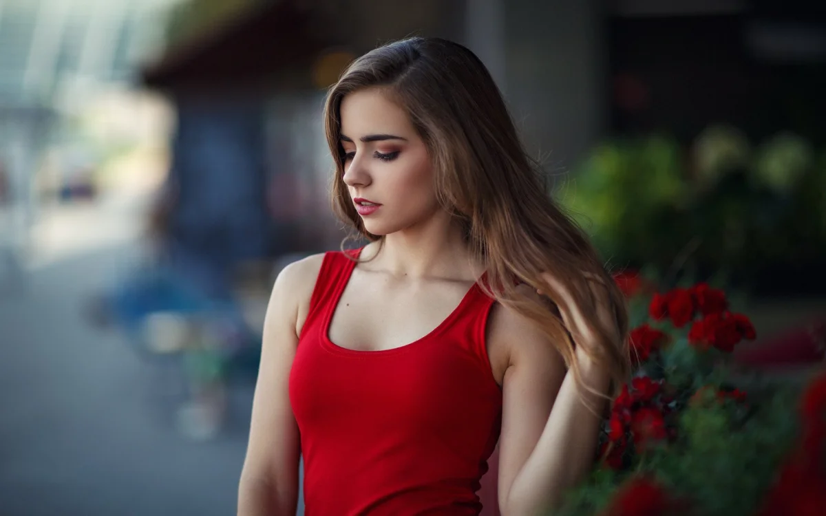 The girl in the red T-shirt is fixing her hair