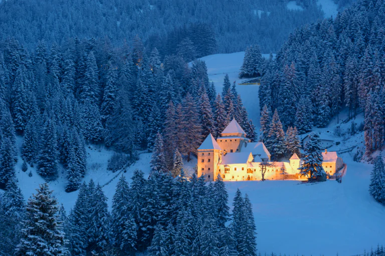 Tarasp Castle at dusk amid the snow-covered forests of Switzerland