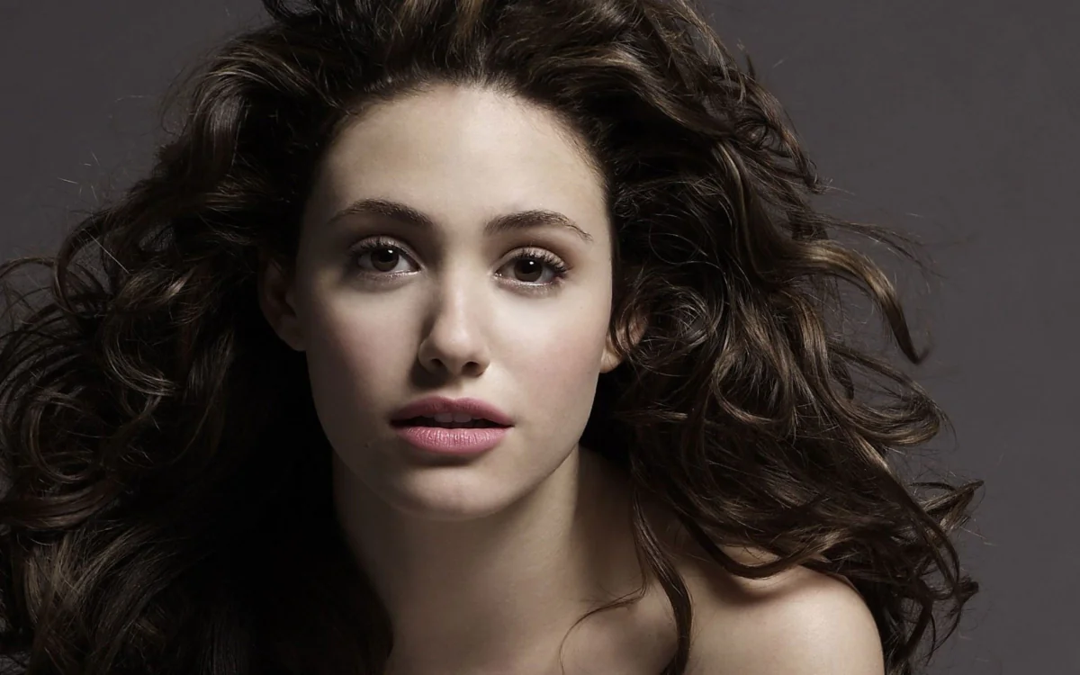 A portrait of Emmy Rossum with voluminous dark curls