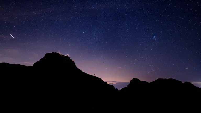 The silhouettes of mountain peaks against a sky studded with stars from the Milky Way