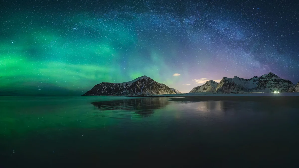 The Northern Lights and the Milky Way over the snow-capped mountains of Norway