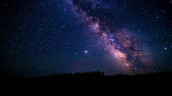 The Milky Way above the silhouette of a dark forest