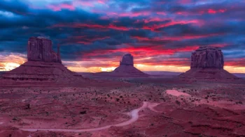 The red cliffs of Monument Valley under a blazing sunset sky