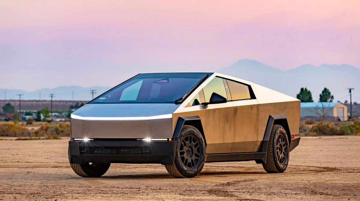 A Tesla Cybertruck against a desert backdrop, bathed in the rays of the setting sun