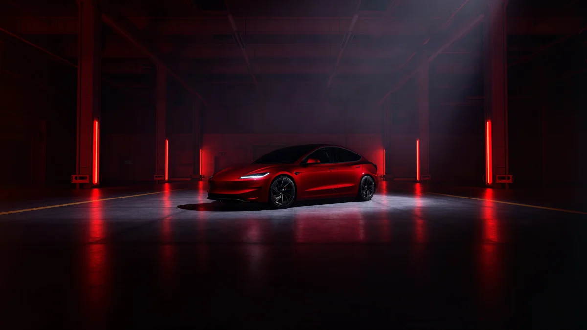 A red Tesla Model 3 bathed in neon light