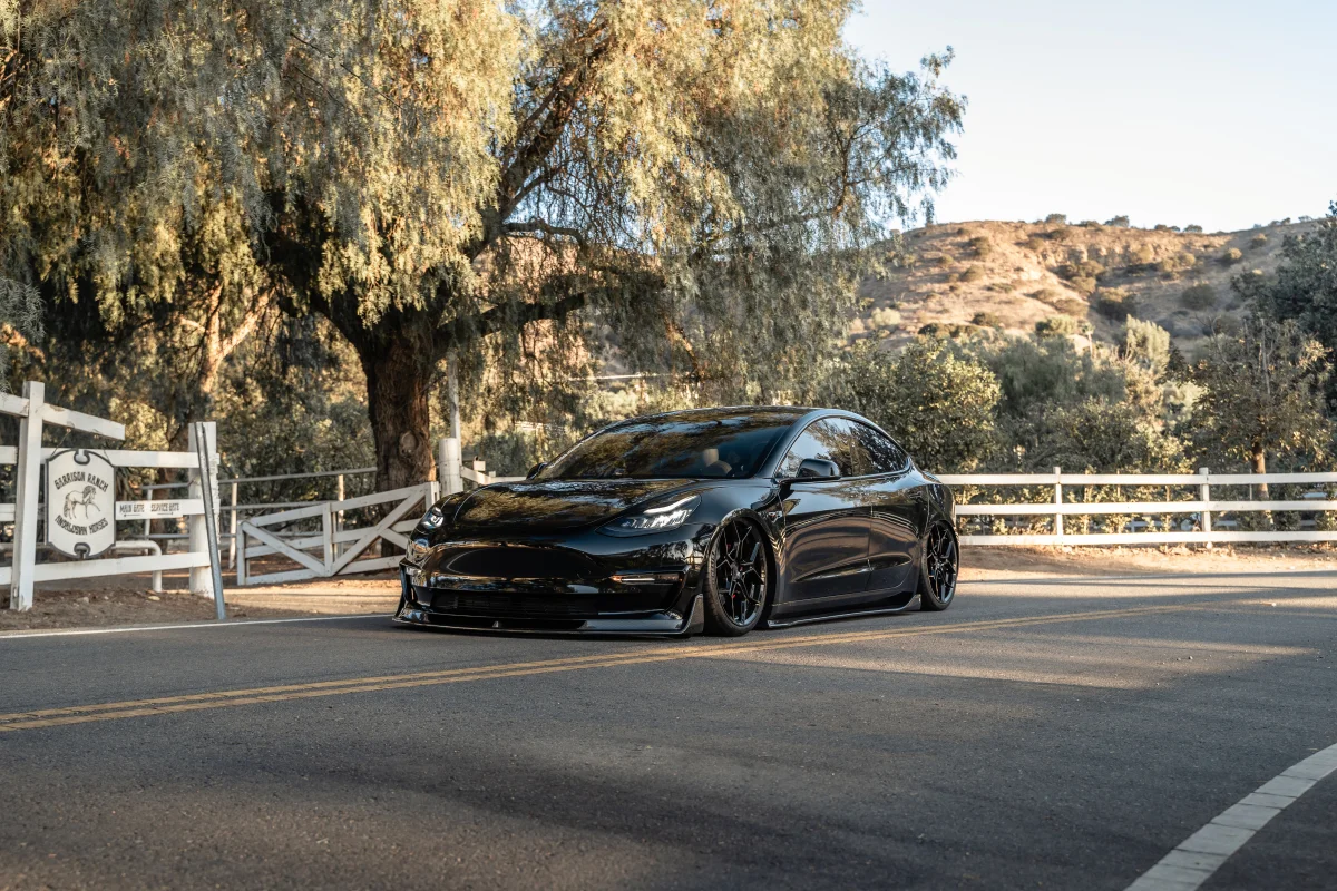 A black Tesla Model 3 against the backdrop of a California ranch