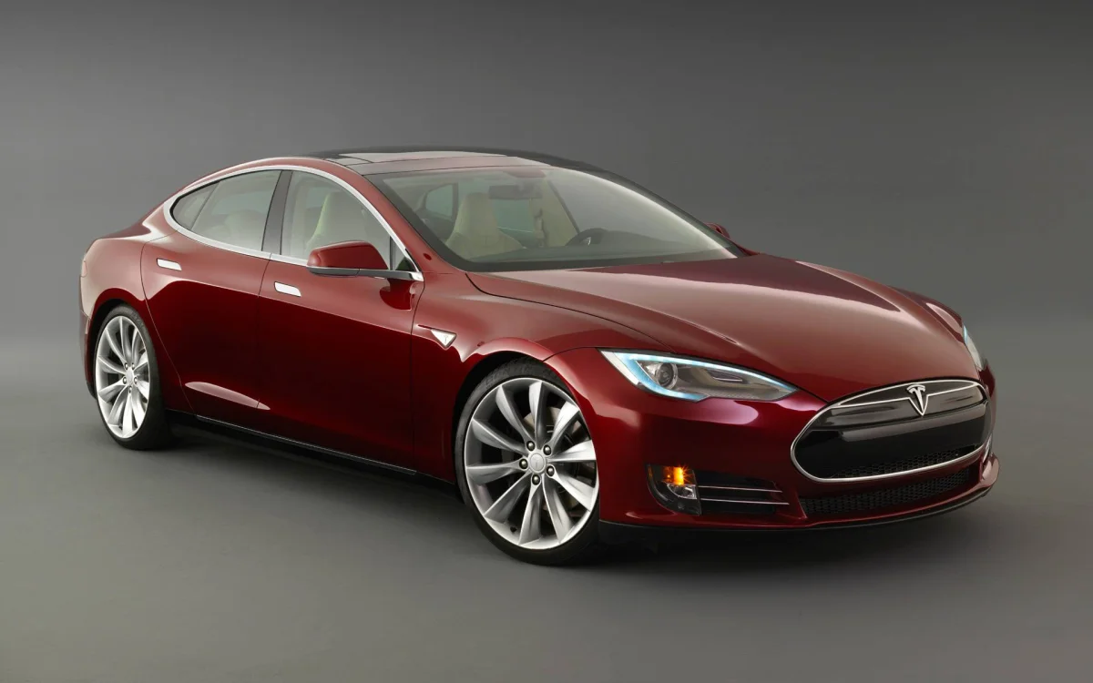 A burgundy Tesla Model S in studio lighting
