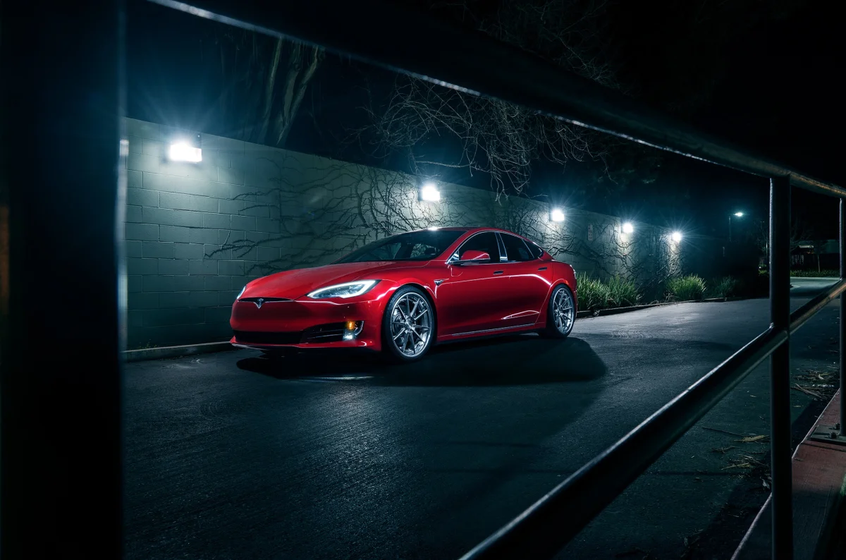 A red Tesla Model S in the light of the streetlamps in the parking lot