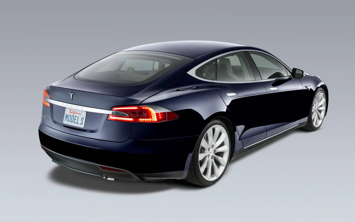 A dark blue Tesla Model S against a studio backdrop