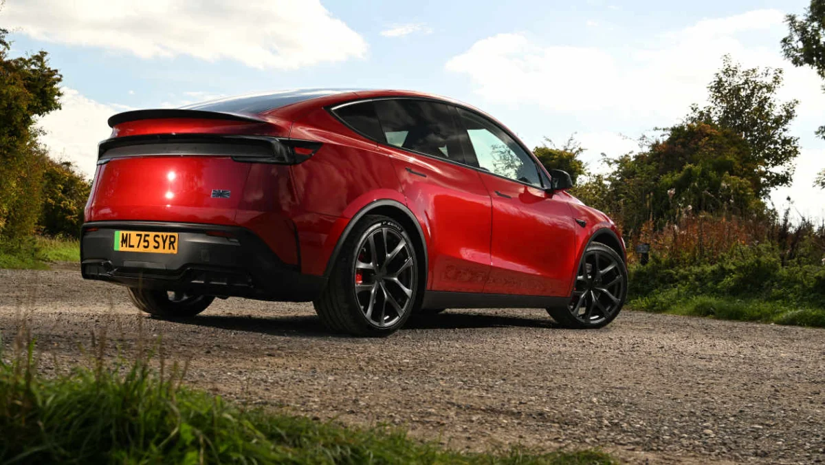 A red Tesla Model Y on a gravel road