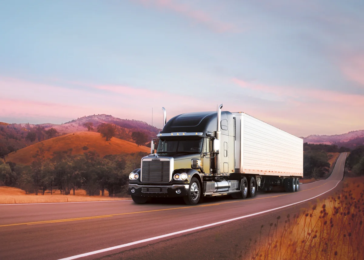 A Freightliner truck against the backdrop of the sunset-lit hills
