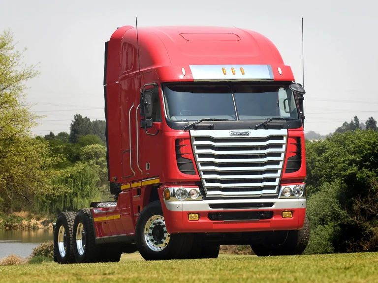 Красный тягач Freightliner Argosy на фоне летнего пейзажа