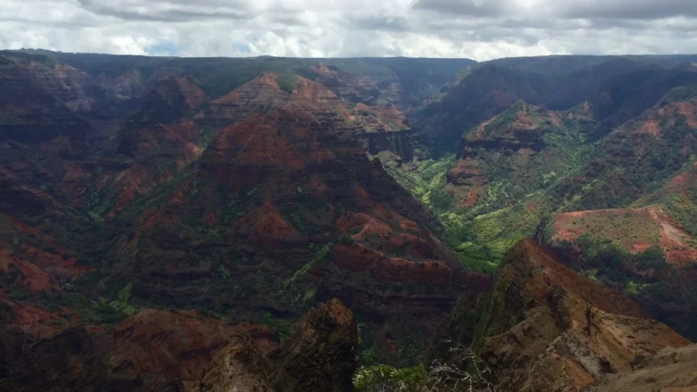 The deep gorges of Waimea Canyon beneath Hawaii's cloudy sky