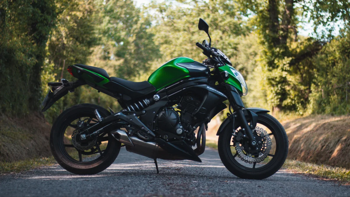 Зелений Kawasaki ER-6n на лісовій дорозі у променях сонця