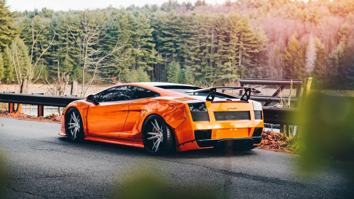 A bright orange Lamborghini Gallardo against the backdrop of an autumn forest