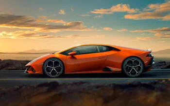 An orange Lamborghini Huracán against the backdrop of a sunset over the sea