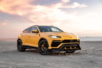A yellow Lamborghini Urus on a sandy beach