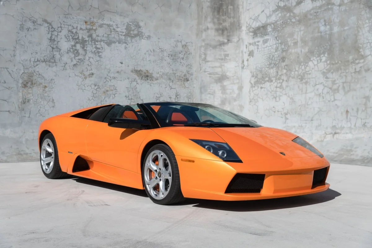 A bright orange Lamborghini Murcielago Roadster against the backdrop of a concrete wall