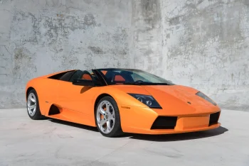 Яскраво-помаранчевий Lamborghini Murcielago Roadster на тлі бетонної стіни