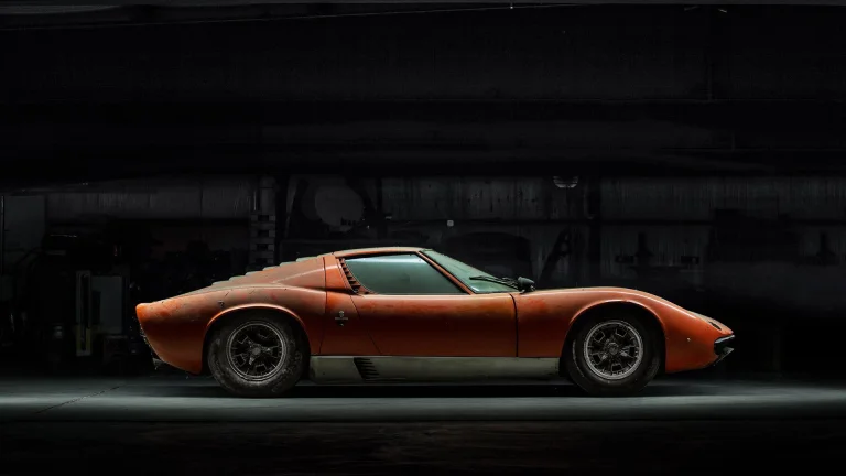 An orange Lamborghini Miura in the dim light of the garage
