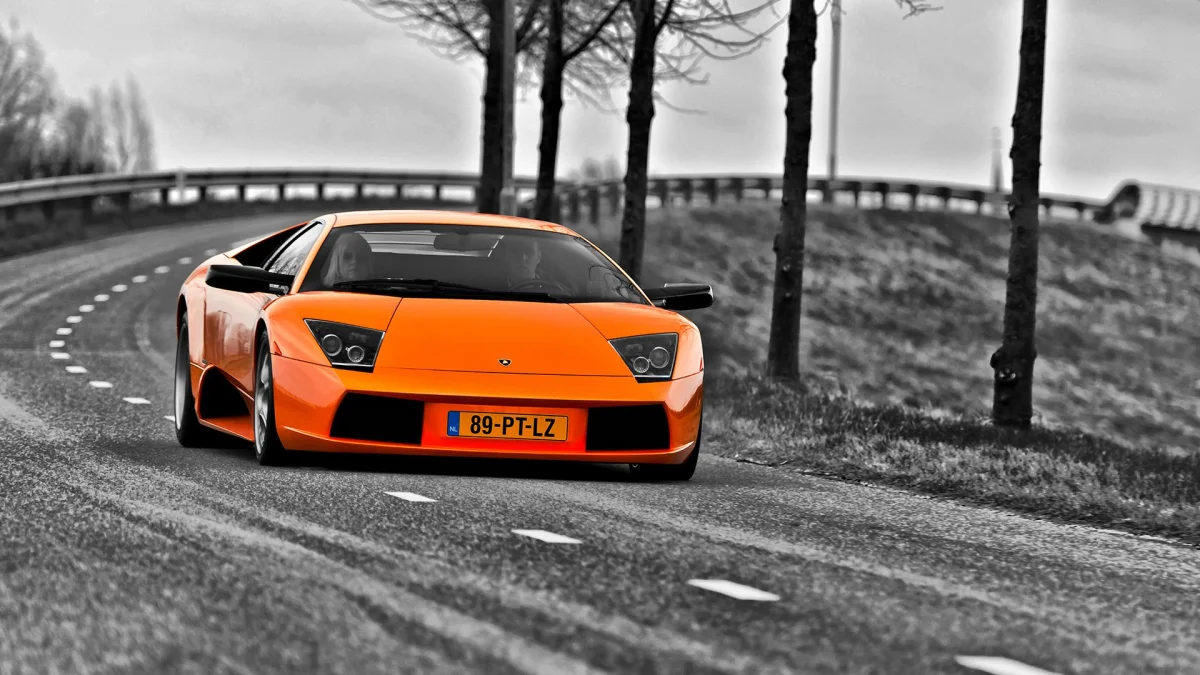 Ярко-оранжевый Lamborghini Murcielago на извилистой пригородной дороге