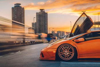 An orange Lamborghini Murcielago against the backdrop of Tokyo at dusk