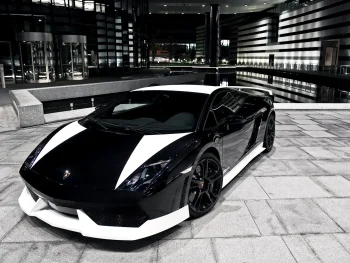Чорно-біла Lamborghini Gallardo на тлі нічного міського пейзажу