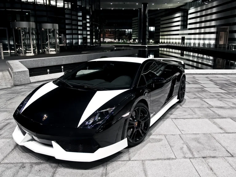 Чорно-біла Lamborghini Gallardo на тлі нічного міського пейзажу