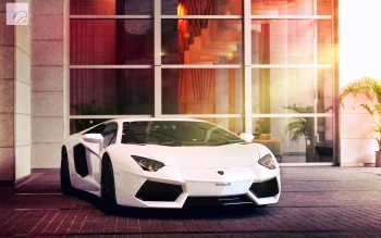 A snow-white Lamborghini Aventador in front of a glass facade