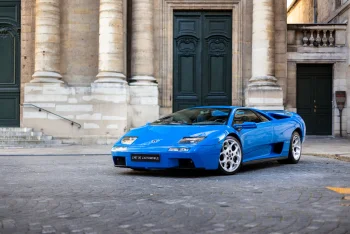 A bright blue Lamborghini Diablo against the backdrop of a historic Parisian building