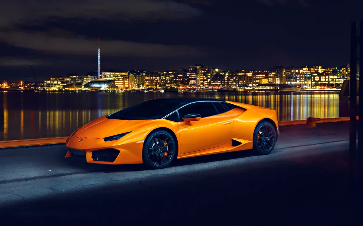 Оранжевый Lamborghini Huracan на фоне ночной набережной Осло