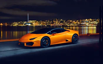 An orange Lamborghini Huracan against the backdrop of Oslo's waterfront at night