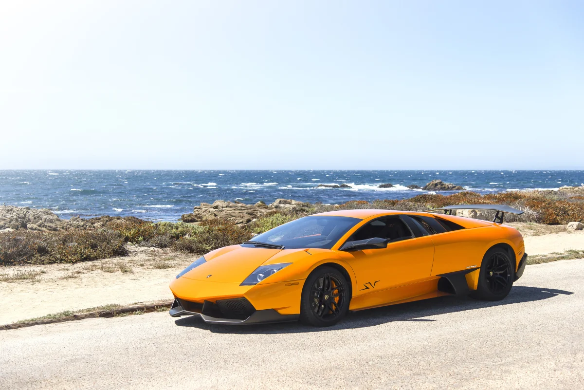 Ярко-оранжевый Lamborghini Murcielago SV на прибрежной дороге