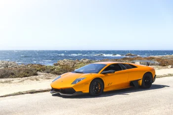Ярко-оранжевый Lamborghini Murcielago SV на прибрежной дороге