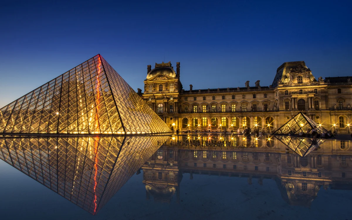 The lights of Paris at night and the glass pyramid of the Louvre