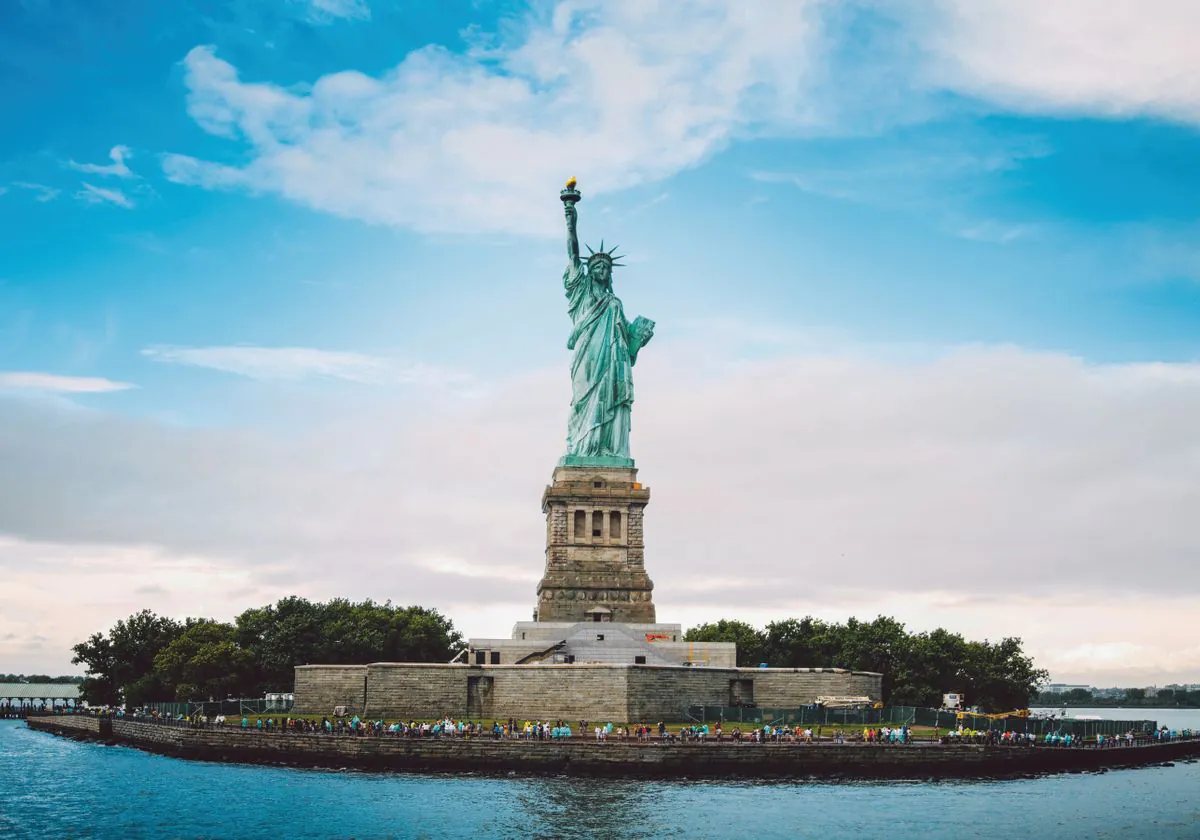 the statue of liberty against the backdrop of new york city, statue of liberty, attractions, cities, city, clouds, islands, monuments, new york, sky, statues, usa, united states, architecture, world