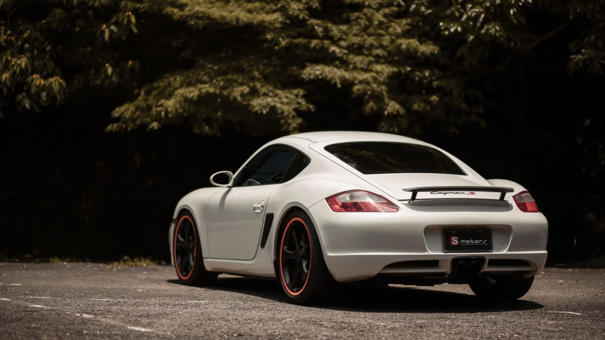 Белый Porsche Cayman S на лесной дороге