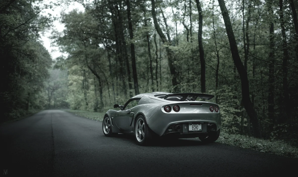 Сріблястий Lotus Exige на порожній лісовій дорозі